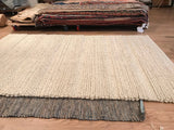 Chunky undyed wool Snow rug texture layered above a dark woven natural fiber mat.