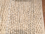 Detail of Snow Collection rug's undyed wool, showing rows of chunky knots and braided segments.