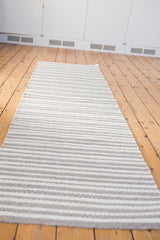 Angled view of the modern hand-woven undyed wool rug with gray and white stripes.