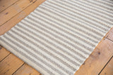 Geometric hand-woven undyed wool rug with textured gray and white stripes.
