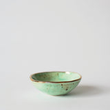 Handmade mint ceramic ring dish with a gold luster rim and uneven hand-painted surface.