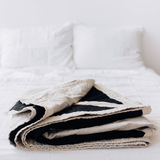 Folded Louise Gray quilt showcasing black, cream, and flax cotton linen.