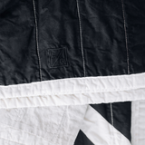 Embroidered LG logo on black and cream Louise Gray cotton linen quilt.