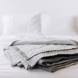 Folded Louise Gray quilt, with light gray quilted and dark gray textured fabric.