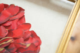 Hand-arranged ruby red petals of Maria Jareau Heller's 3D flower art with gold frame.
