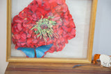 Right side of the gold shadow box frame and layered dark pink flower, blue butterfly artwork.