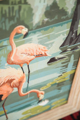 Close-up of faded pink flamingos in vintage paint by numbers painting with scrapes.