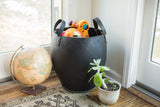 Recycled rubber basket's black textured base, showing white stitching and a plant.