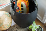 Textured black recycled rubber basket opening, featuring white stitched handle and yellow toy.