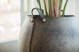 Recycled rubber basket, close-up of textured tire tread, stitched seam, and handle detail.