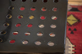 Black lacquered metal chair surface with perforated details and minor wear.