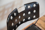 Perforated black lacquered metal backrest with silver bar on vintage chair.