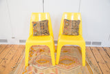 Two brightest yellow Borg Wagner plastic chairs with patterned cushions, sitting on a colorful rug.