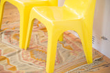 Bright yellow Borg Wagner chair legs resting on a muted hand-knotted rug.