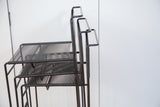 Stacked black spaghetti barstools, highlighting linear textured seats and backs.
