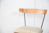 Vintage Clifford Pascoe chair's curved birchwood backrest with visible signs of age and gray seat.