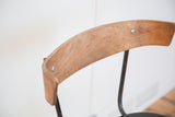 Curved light brown wooden backrest with visible grain and black iron frame.