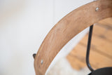 Curved wooden backrest of the vintage barstool, showing subtle markings and metal rivets.