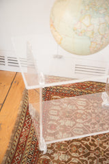 Transparent top of vintage Lucite rolling cart table with faint surface marks.