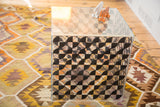 Angled view of vintage Lucite cube side with black checker art and surface wear.