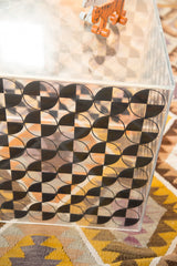 Vintage Lucite cube with black checker art pattern and numerous surface scratches.