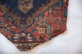 Rustic hand-knotted weave and salvaged edge of an antique Kurdish rug fragment.