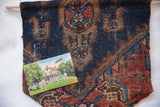 The antique Kurdish rug fragment cork board holding a pinned vintage postcard.