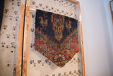 Handmade cork board made from an antique Kurdish Malayer rug fragment, shown hanging from an angle.