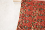 Detail of handcrafted stitching securing the antique rug fragment to its wooden dowel.