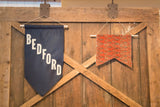 A red antique rug fragment flag displayed as wall art on a rustic wooden door.