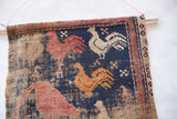 Detail of the antique West Persian rug fragment's corner with colorful rooster renderings.