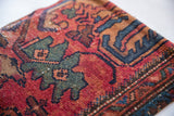 Textured vintage Persian Lilihan rug fragment featuring ruby red and teal motifs.