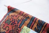 Vintage Lilihan rug fragment's top edge, showing hand-knotted weave, deep red, blue, and dowel.