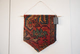 Wooden dowel, copper hanger, and brand tag securing the Lilihan rug fragment wall art.