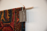 RUGLING wall hanging detail: vintage Persian Lilihan rug fragment, wooden dowel, and RUG ADDICT tag.