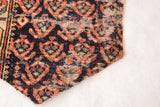 Stitched edge of antique Northwest Persian fragment with dark blue and rust pattern.