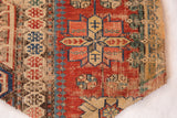 Textured antique Caucasian Soumac rug fragment with geometric motifs in red, blue, and beige.