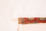 Antique red Soumac rug fragment hand-woven on a wooden dowel.