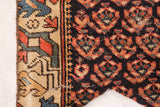 Antique Northwest Persian rug fragment: dark field red motifs, geometric light border, visible stitching.
