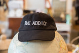 Black Rug Addict embroidered hat resting on a decorative world globe.