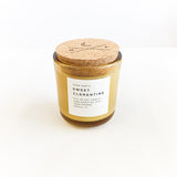 Sweet Clementine soy candle in amber glass with white label and cork lid.