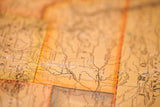 Close-up of an antique map on canvas, showing time-softened hues and visible place names.