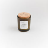 Wanderlust soy candle with its white label showing product details and textured cork lid.