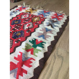 Geometric border of a vintage Turkish Kilim with red, blue, and green star motifs.