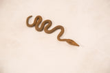 The full coiled form of a vintage handmade iron snake with a rustic patina.