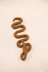Expressive serpentine shape of a vintage handmade iron snake with a rusted patina.