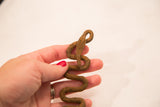 Handmade form and rusted, textured surface of a vintage iron snake sculpture held in hand.