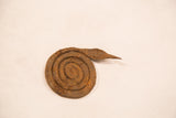 Handmade coiled iron snake gold weight with aged, textured rust.
