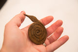 Vintage coiled iron snake sculpture, showing its rustic texture in a hand.