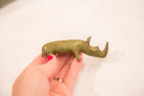 Small vintage bronze rhinoceros held in hand, showing its green patina and scale.